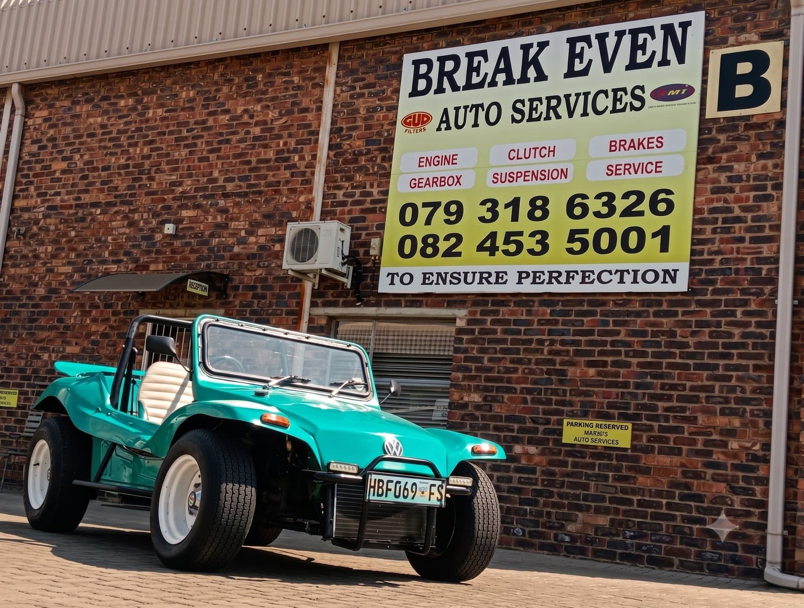 A customer's car parked outside Break Even Auto Services beneath the workshop's services board